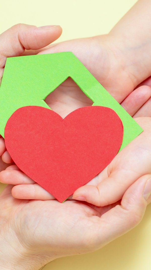 hands_holds_green_paper_house_with_red_heart