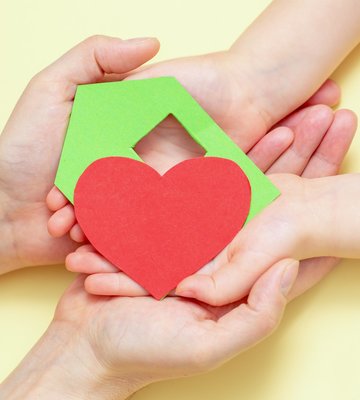 hands_holds_green_paper_house_with_red_heart