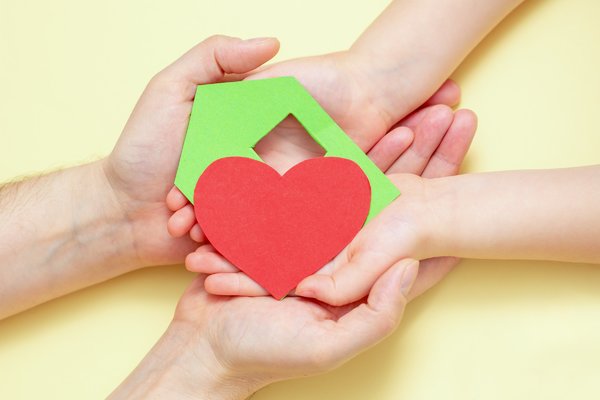 hands_holds_green_paper_house_with_red_heart